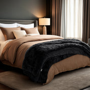 Neatly made bed and a textured throw blanket  over the end of the bed.