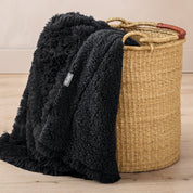 A blanket hanging over the edge of a wicker basket