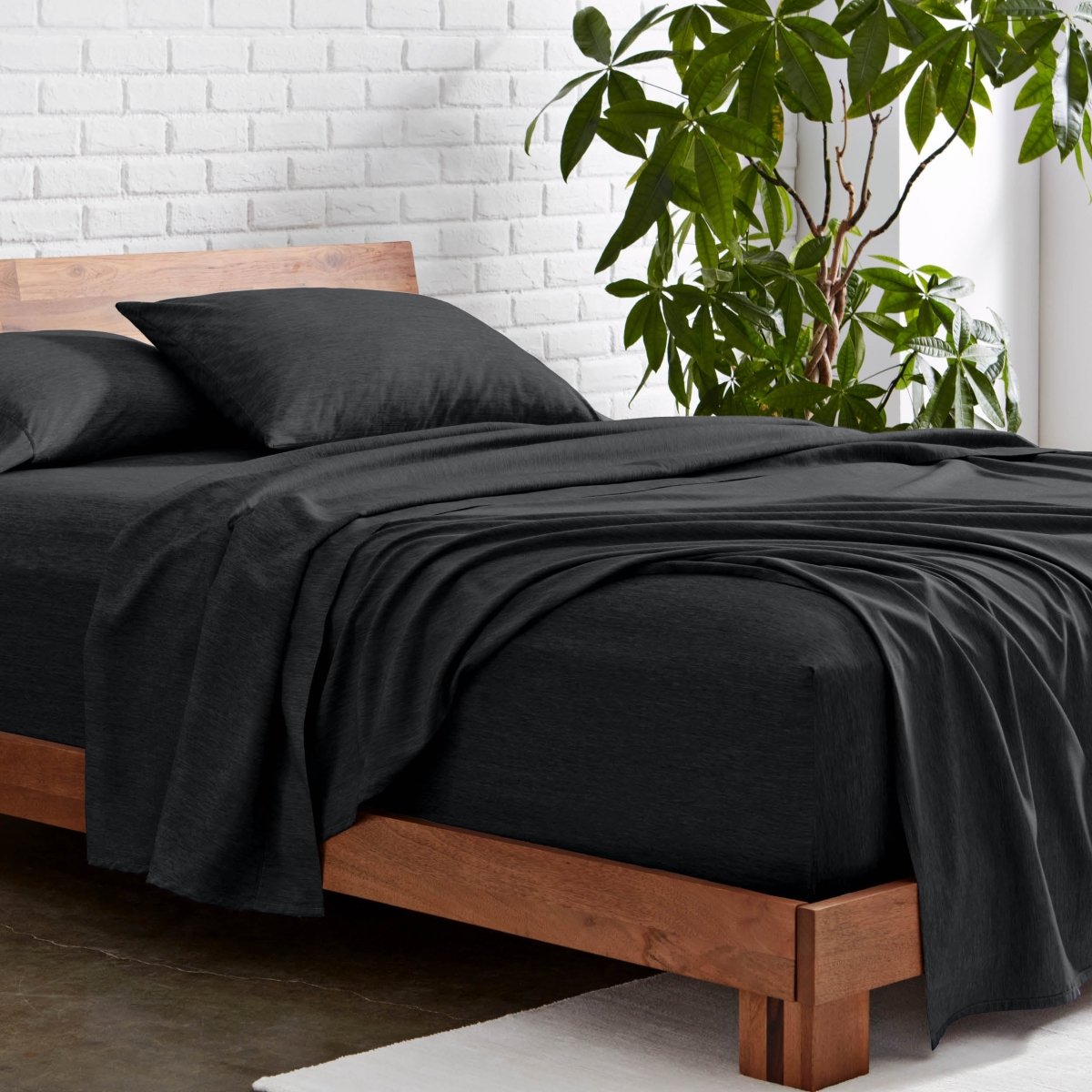 Microfiber sheet set on a wooden bed with a plant in the background