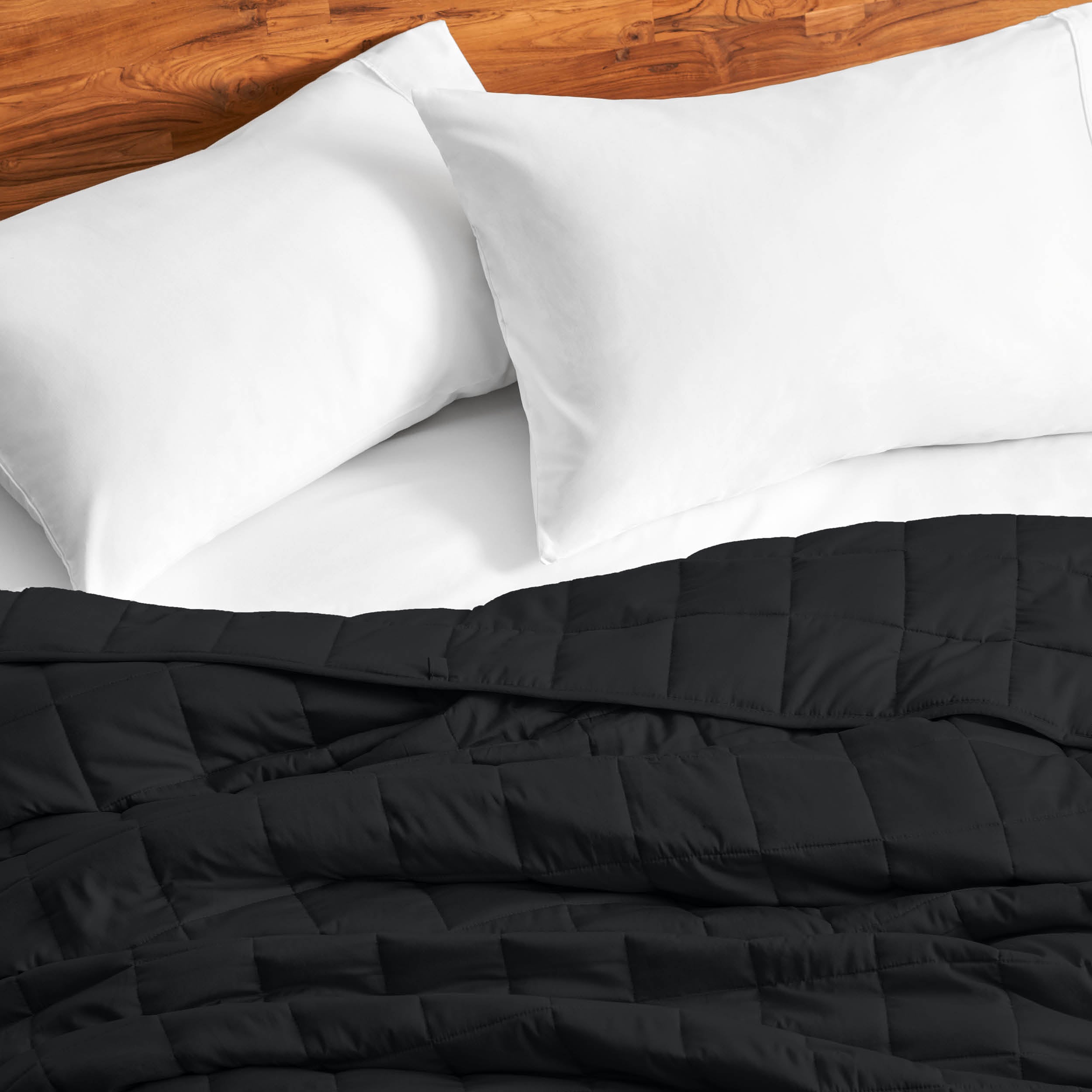 Cotton weighted blanket on a bed with white pillows against a wooden headboard.