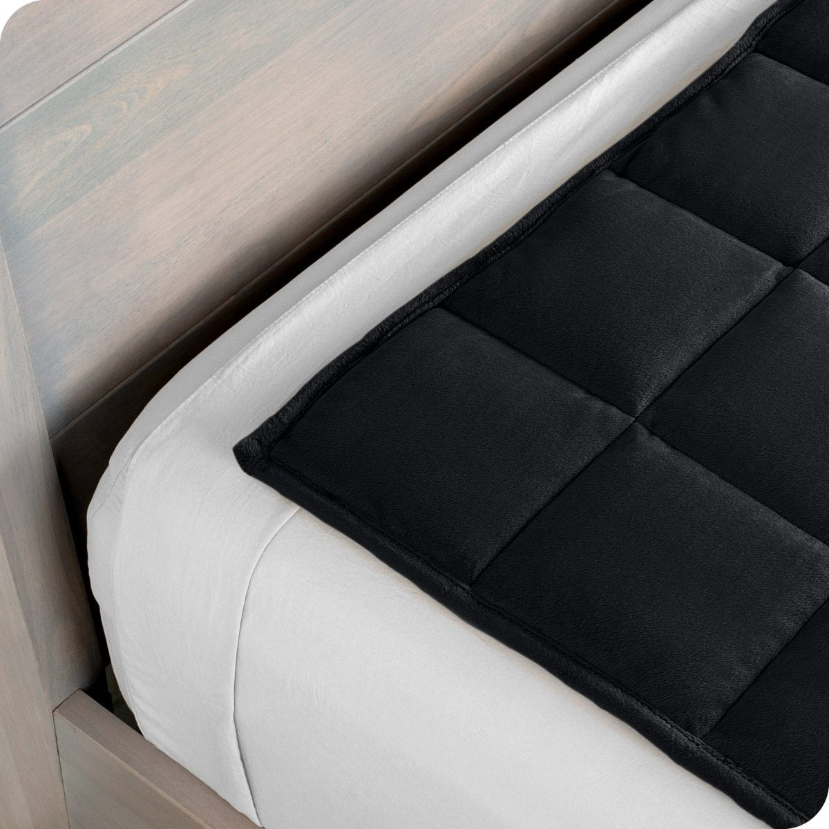Close up of a weighted blanket on top of a bed made with white sheets