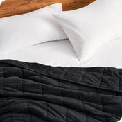 Close up of a weighted blanket on a bed next to pillows