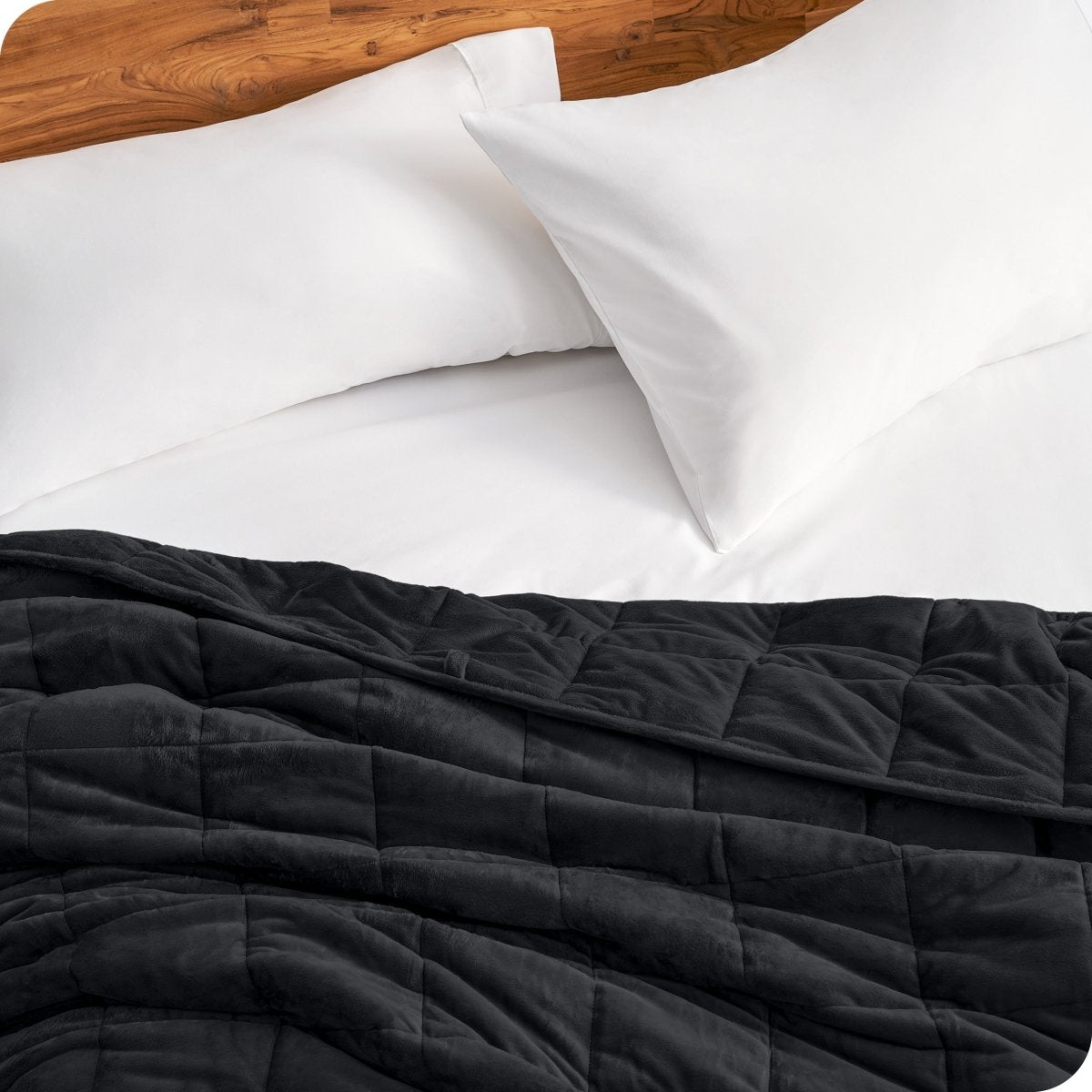 Close up of a weighted blanket on a bed next to pillows
