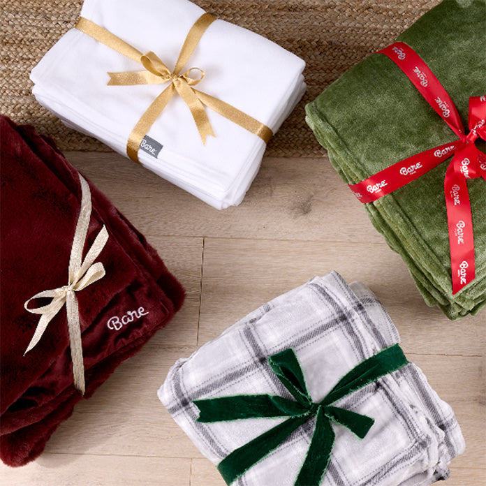 Four folded blankets with ribbons on a wooden surface