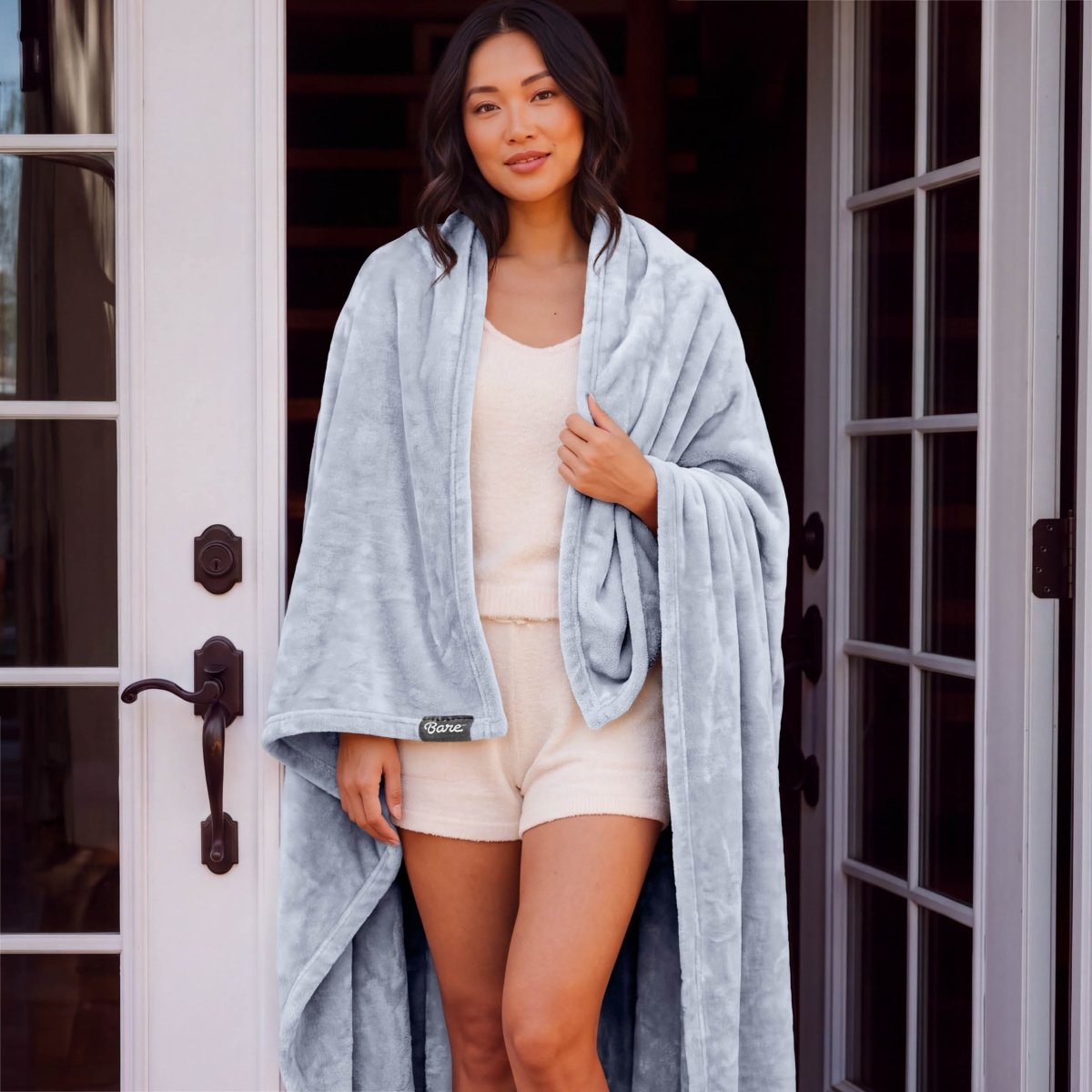 A woman standing with a microplush blanket wrapped around her