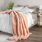 Blanket draped over a bed in a bedroom setting with a nightstand and lamp.