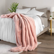Blanket draped over a bed in a bedroom setting with a nightstand and lamp.