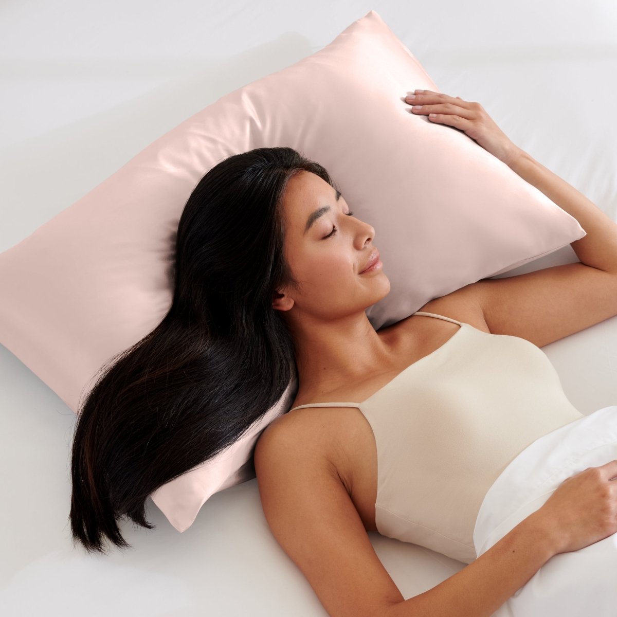 Woman lying on a bed with a pillow covered with a satin pillowcase