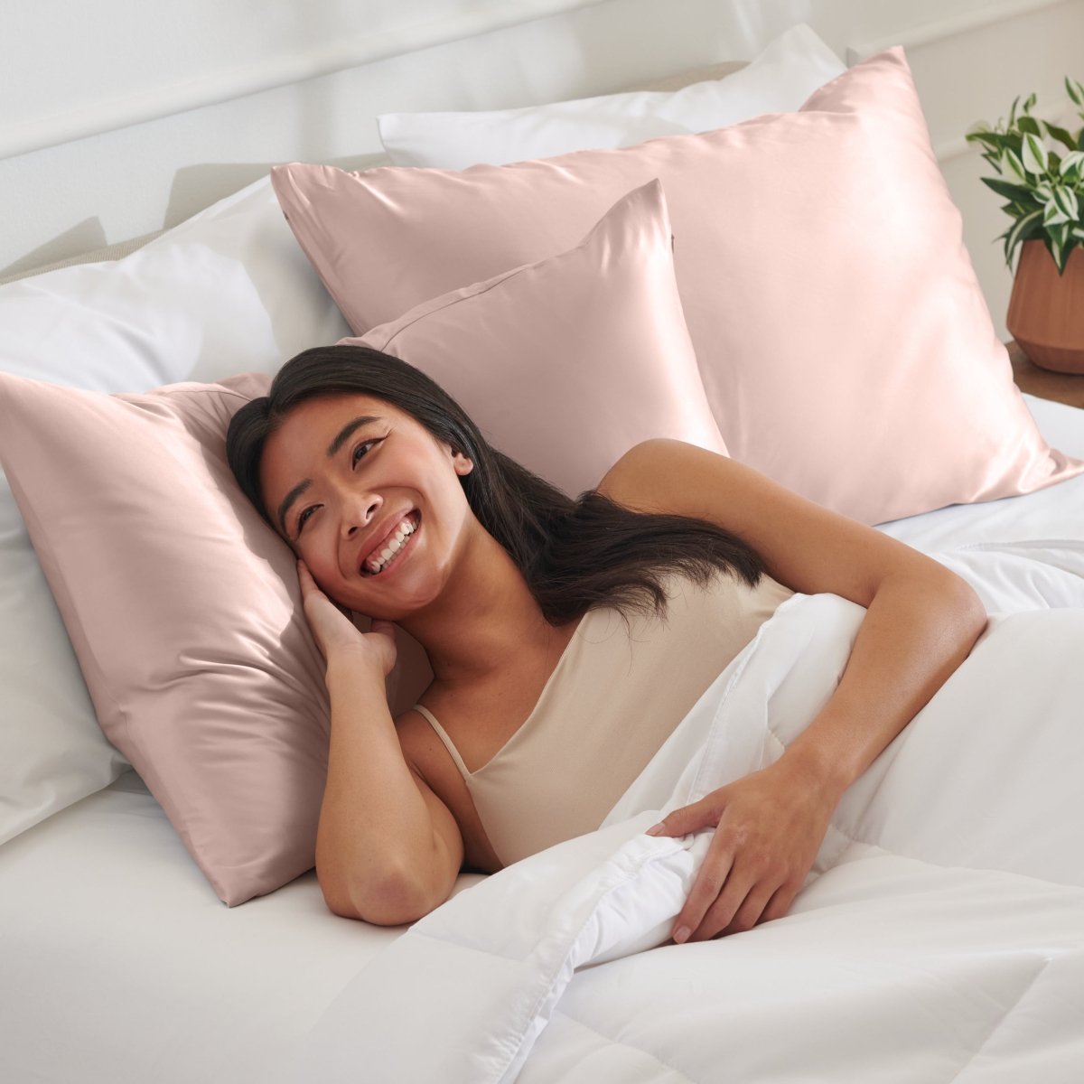 Woman lying on a bed with satin pillows and white bedding