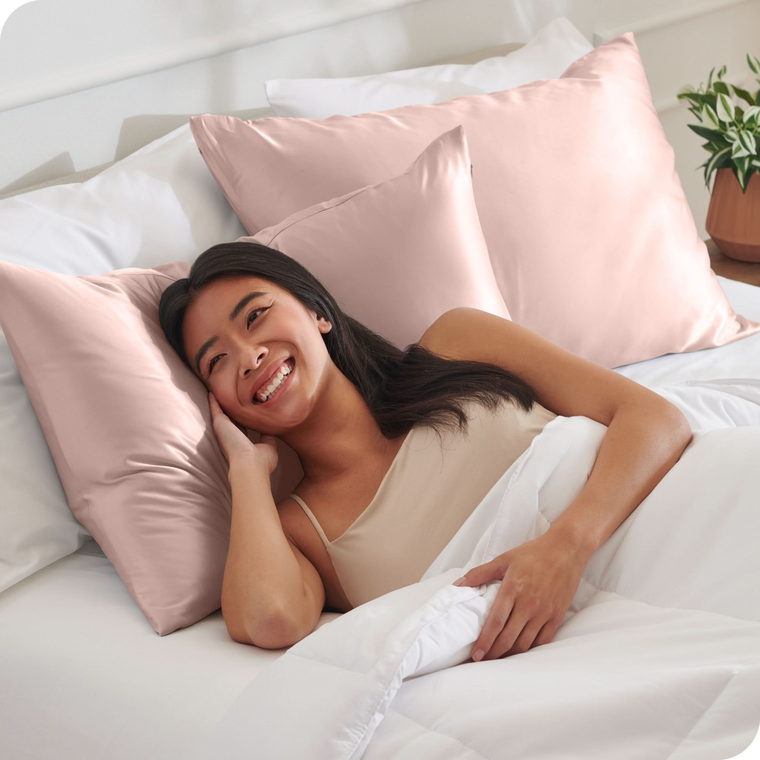 A woman is in bed and resting her head on a satin pillowcase