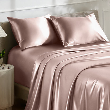 Satin bedding set on a bed with a nightstand and lamp in the background.