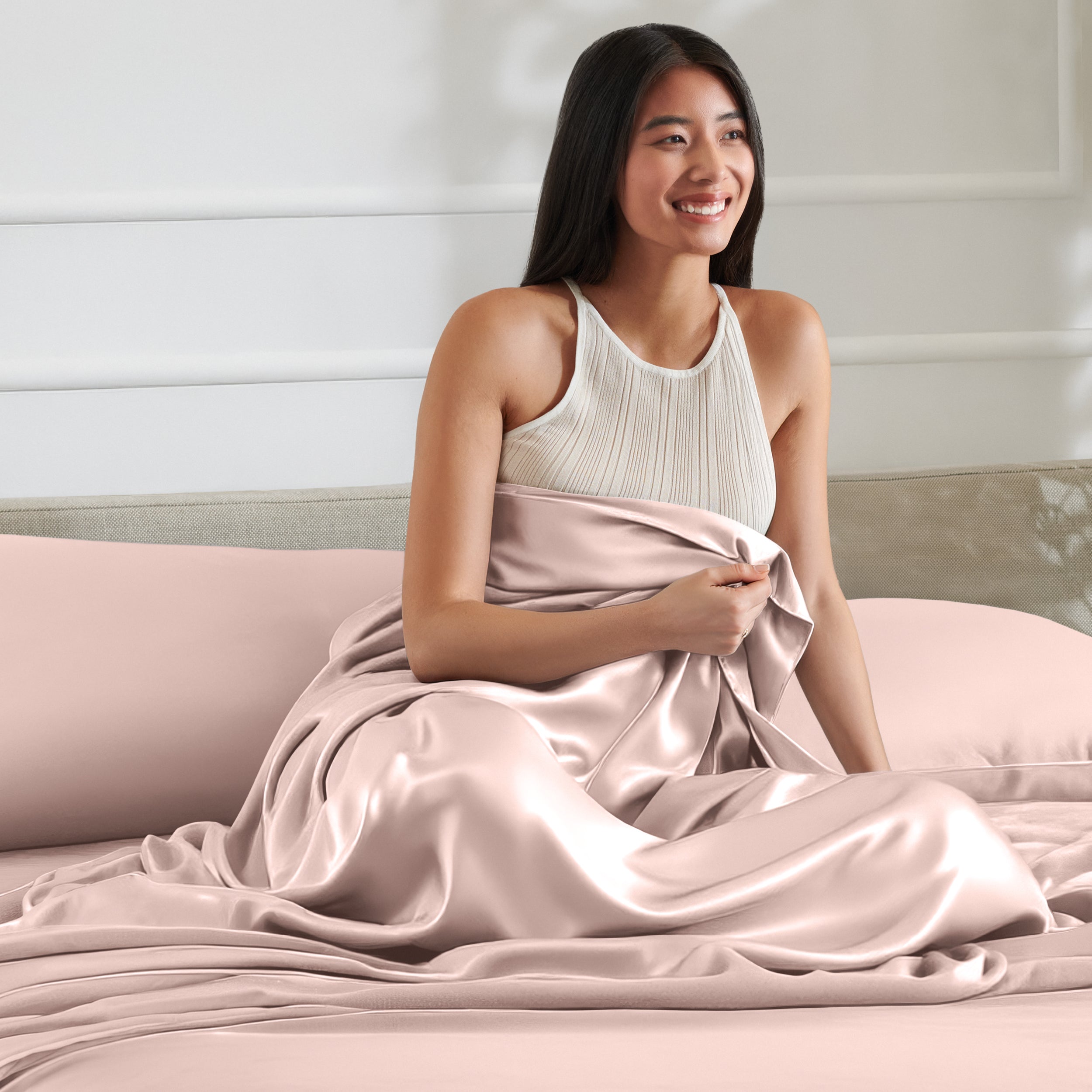Woman sitting on a bed with satin sheets