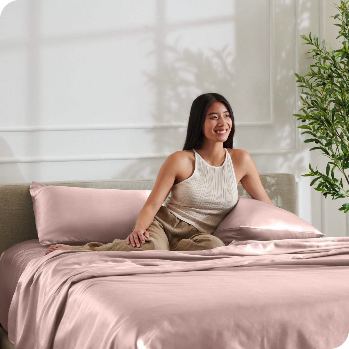 A woman is resting on a bed make with satin sheets