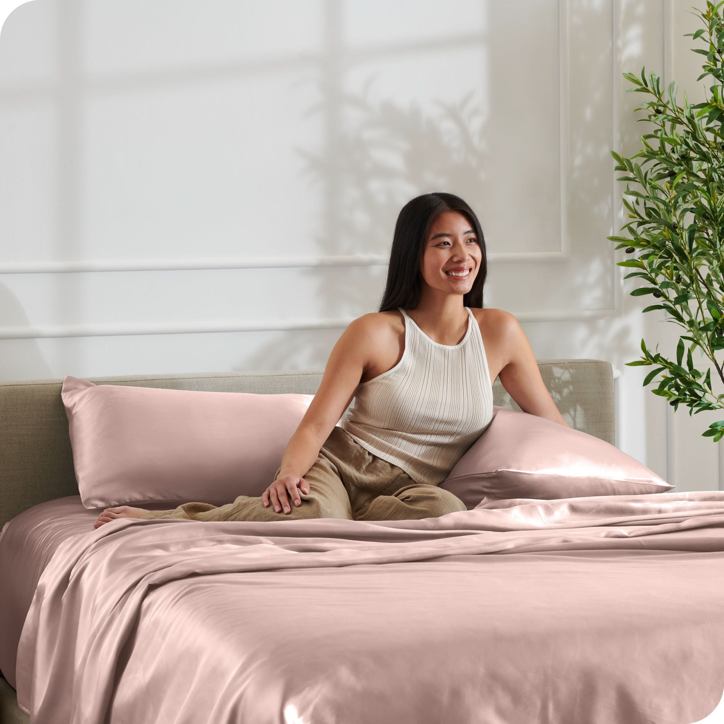 A woman is resting on a bed make with satin sheets