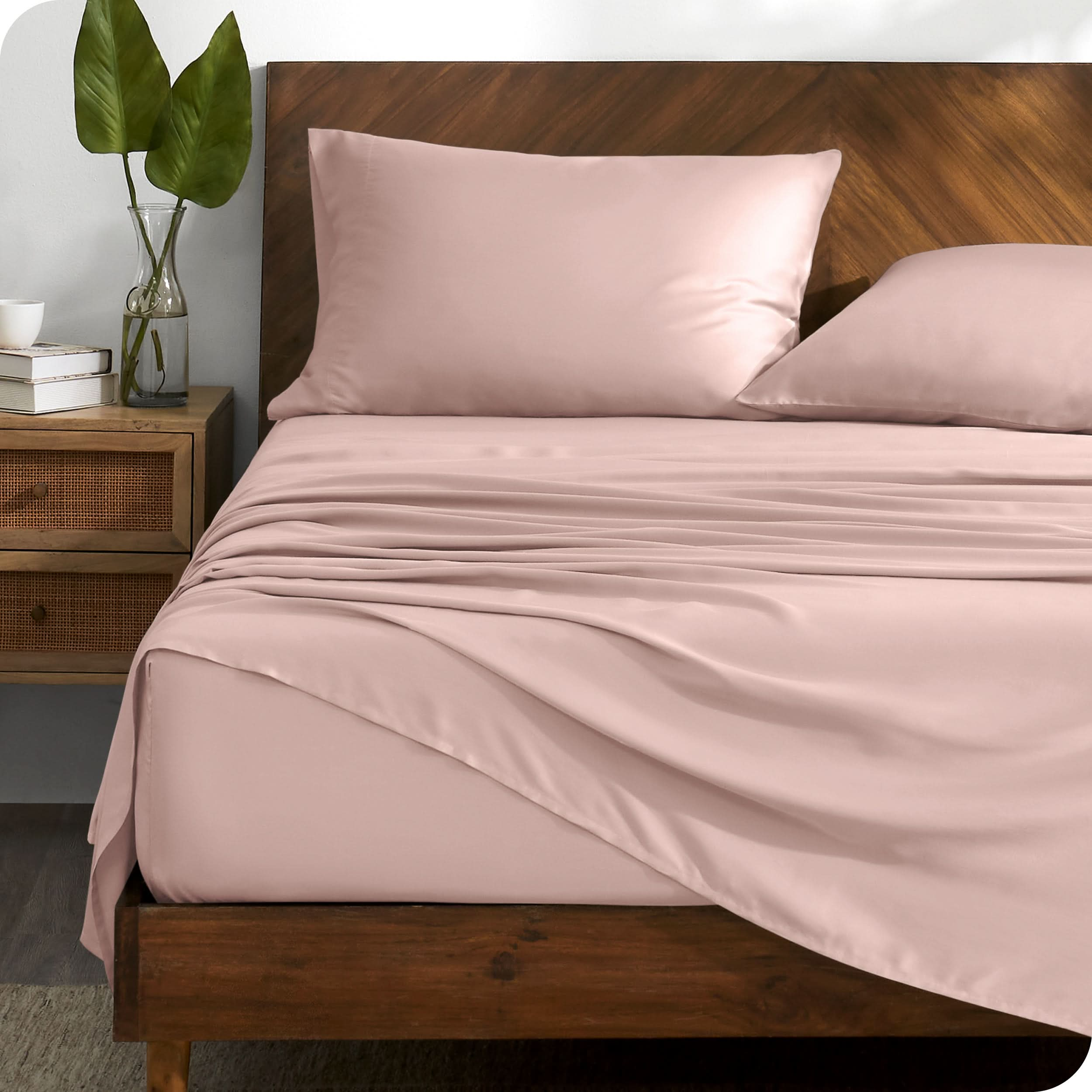 TENCEL™ sheet set on a bed with the flat sheet loosely draped over the top. The mattress is on a wooden bed frame.