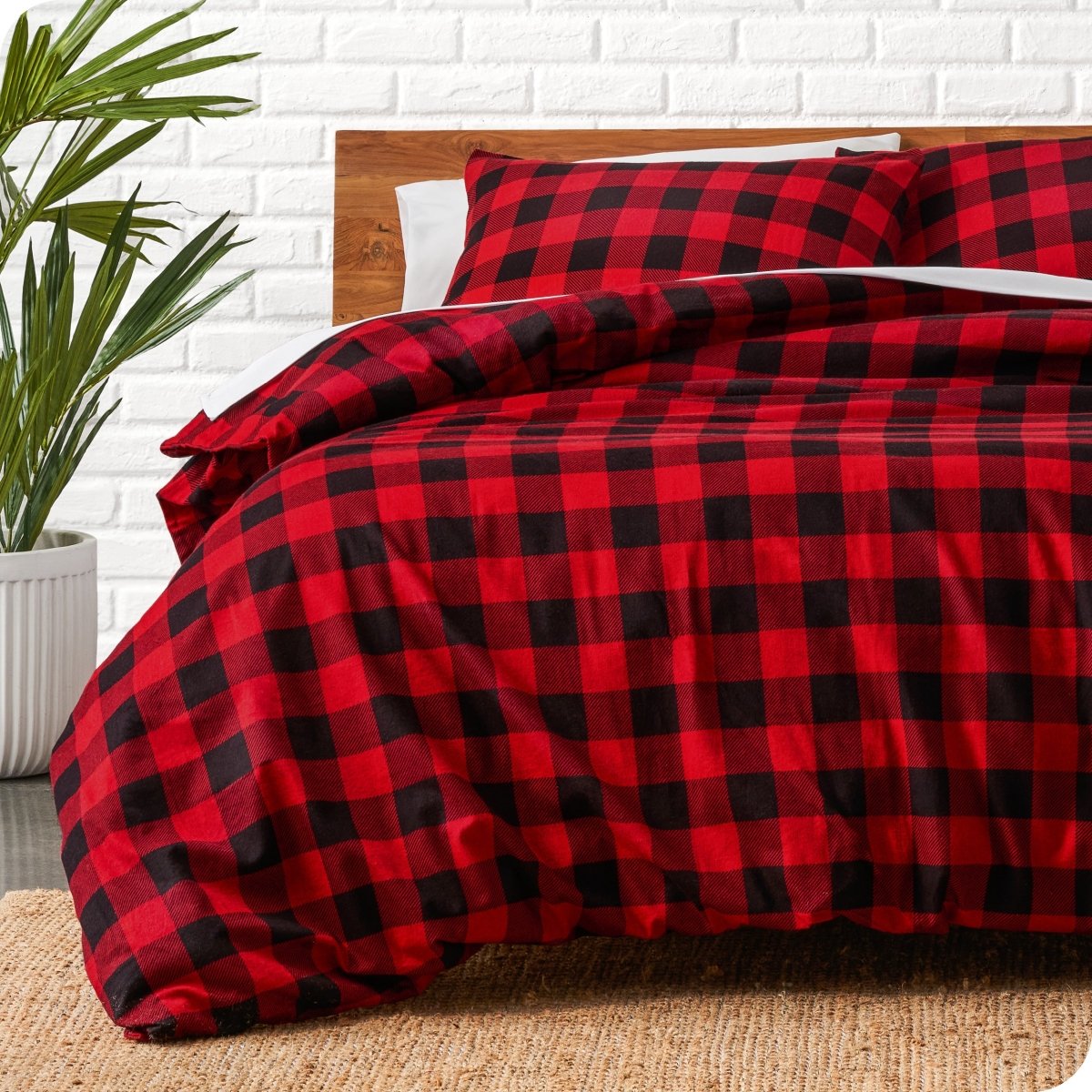 Red and black checkered duvet cover set on a bed with a white brick wall background.