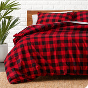 Red and black checkered duvet cover set on a bed with a white brick wall background.