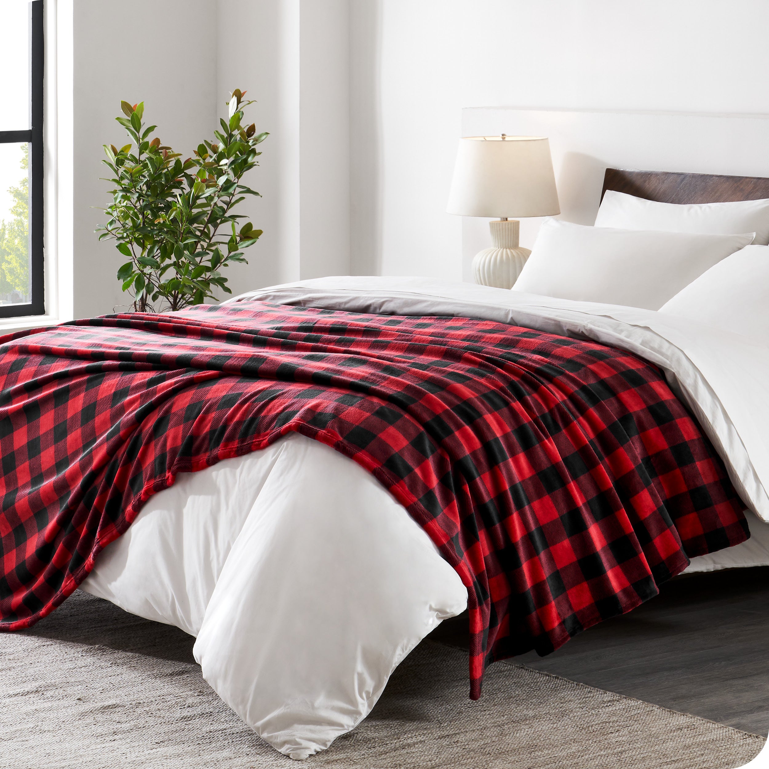 Red and black checkered blanket on a bed in a bedroom setting