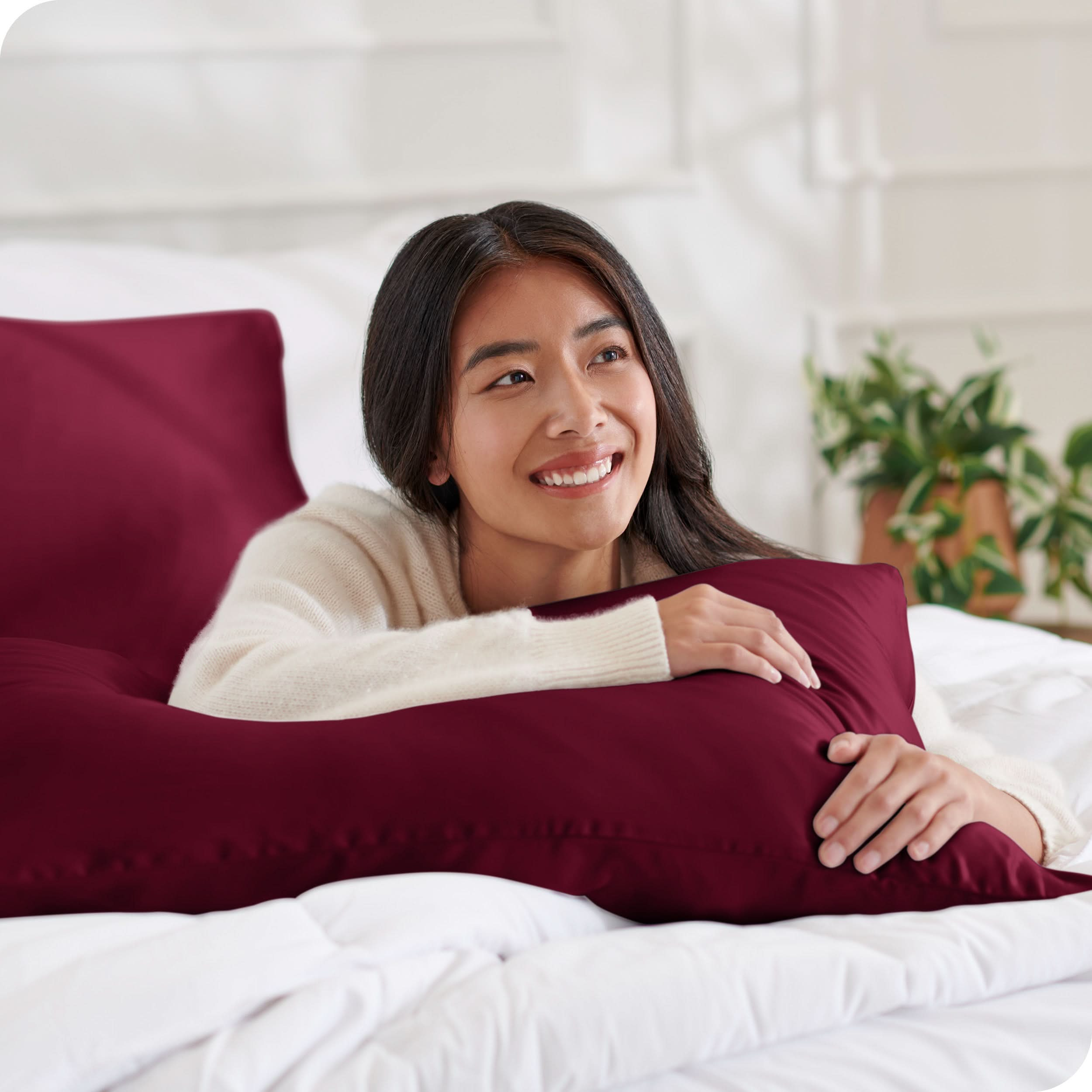 A woman on a bed with a silk pillowcase covered pillow