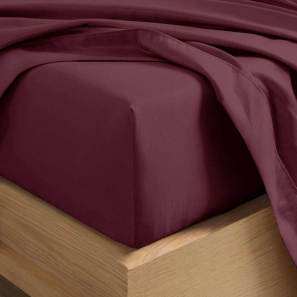 Close up of the corner of a mattress with a fitted sheet and flat sheet on it