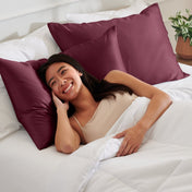 Woman lying on a bed with satin pillows and white bedding