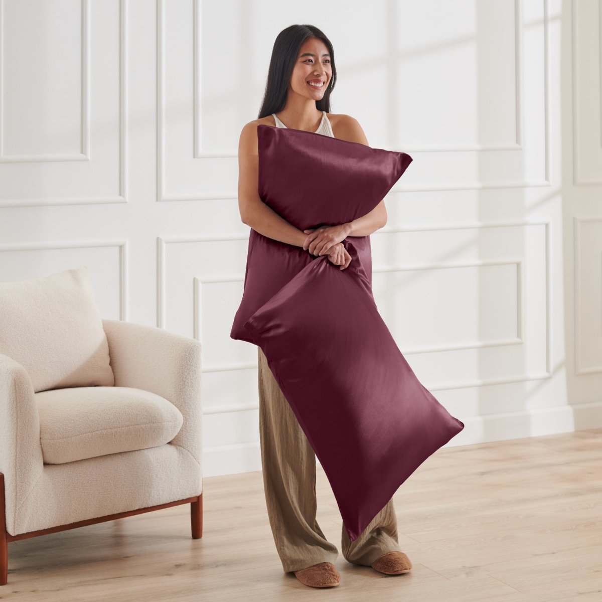 Woman holding 2 pillows with satin pillowcases on them