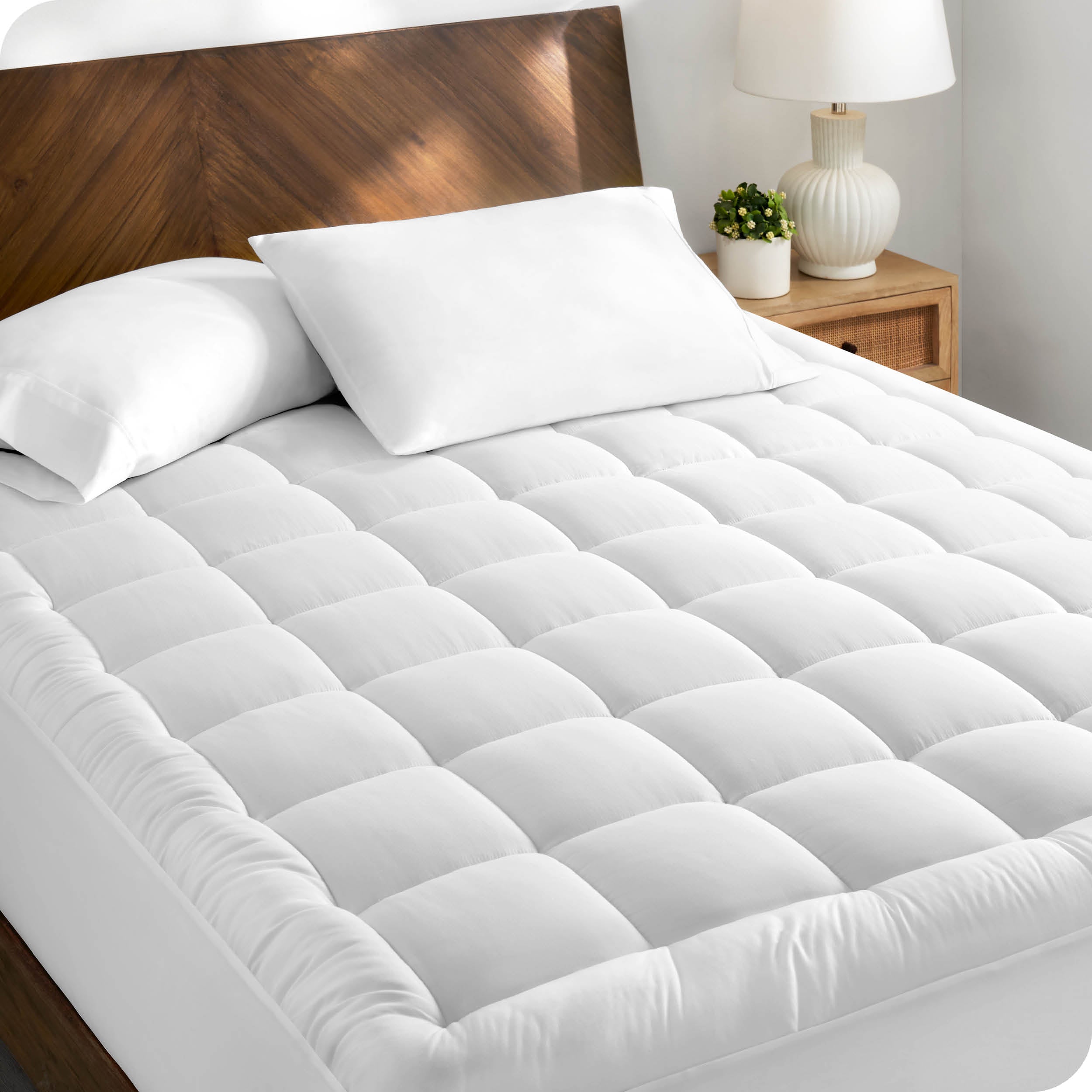 A cotton top mattress pad on a mattress in a modern bedroom.
