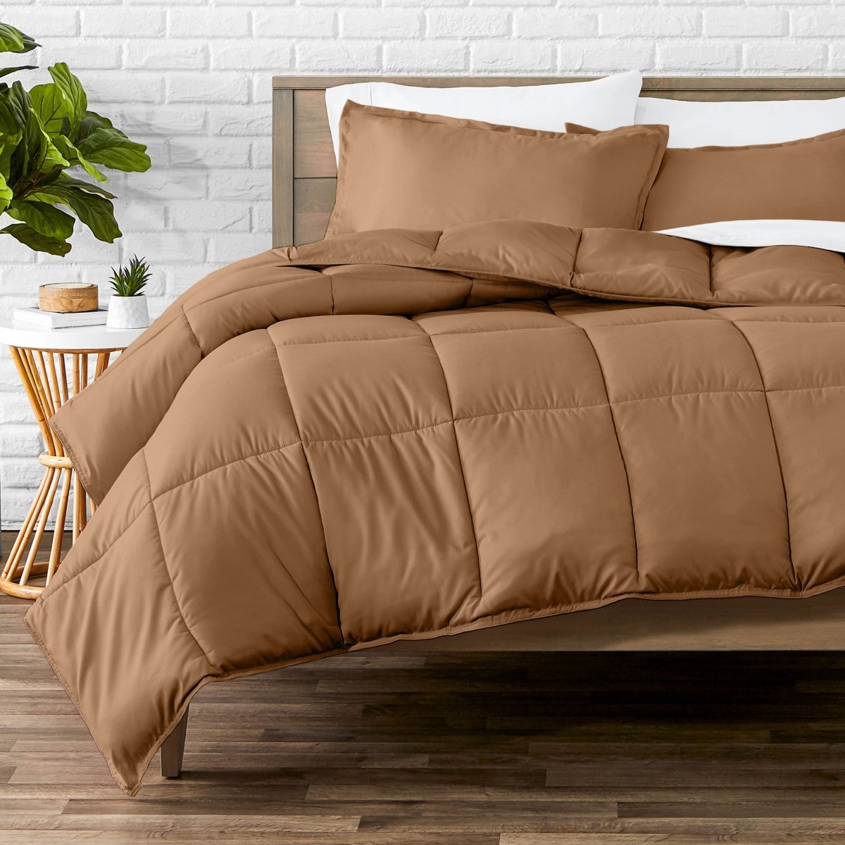 Comforter set on a bed with a white brick wall and plant in the background