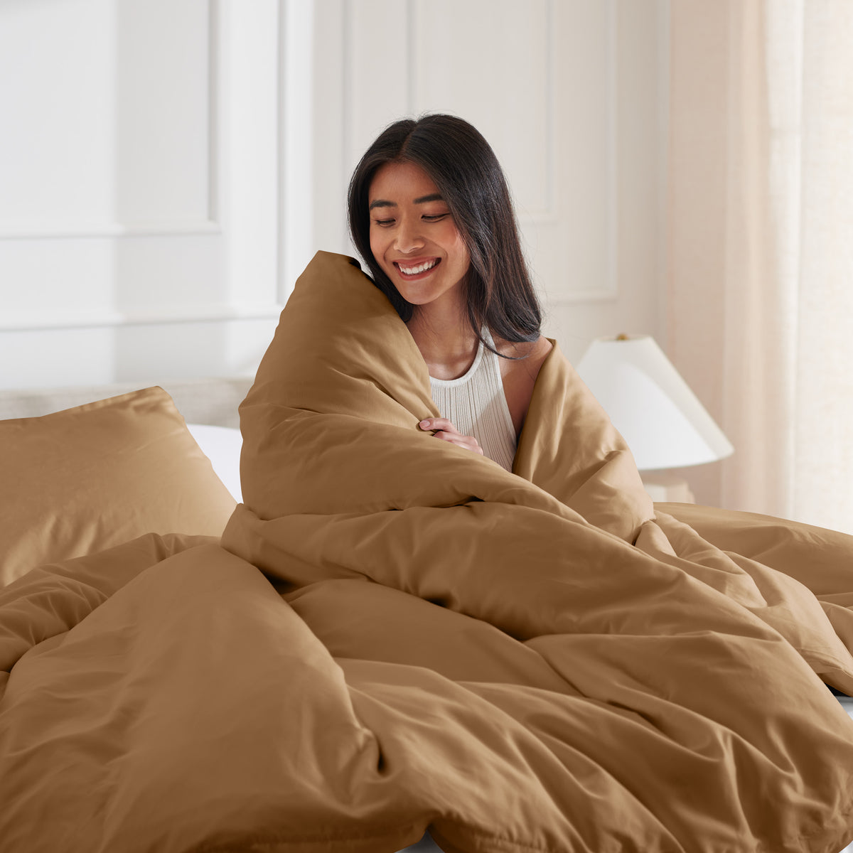 Woman smiling under duvet cover set in a bedroom setting