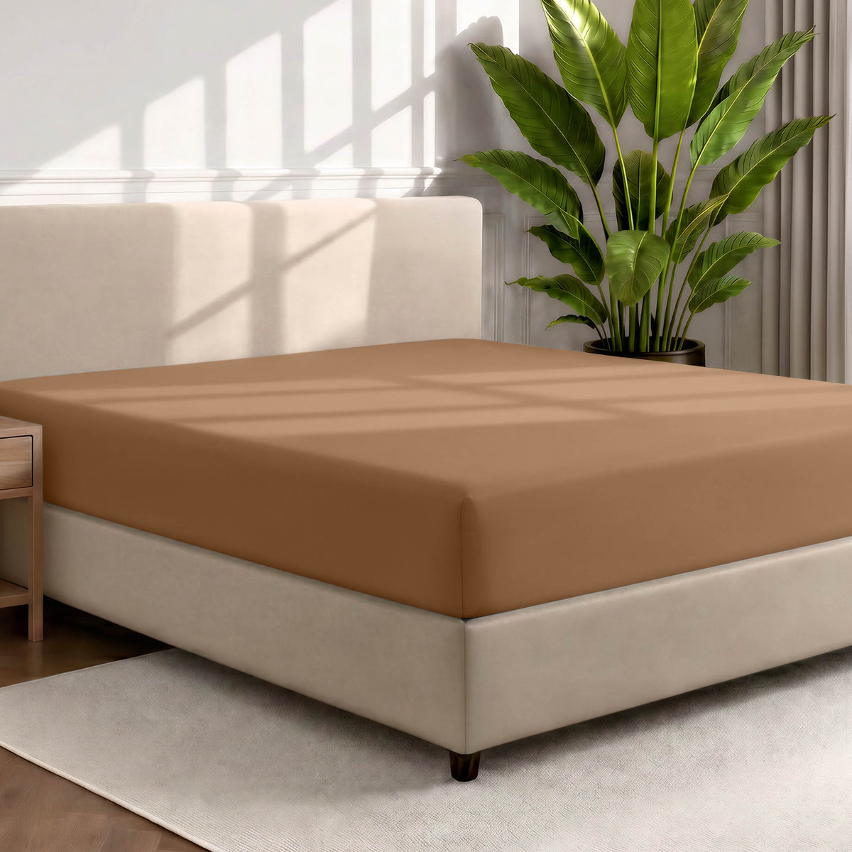 Bed with a fitted sheet in a room with a large plant and rug