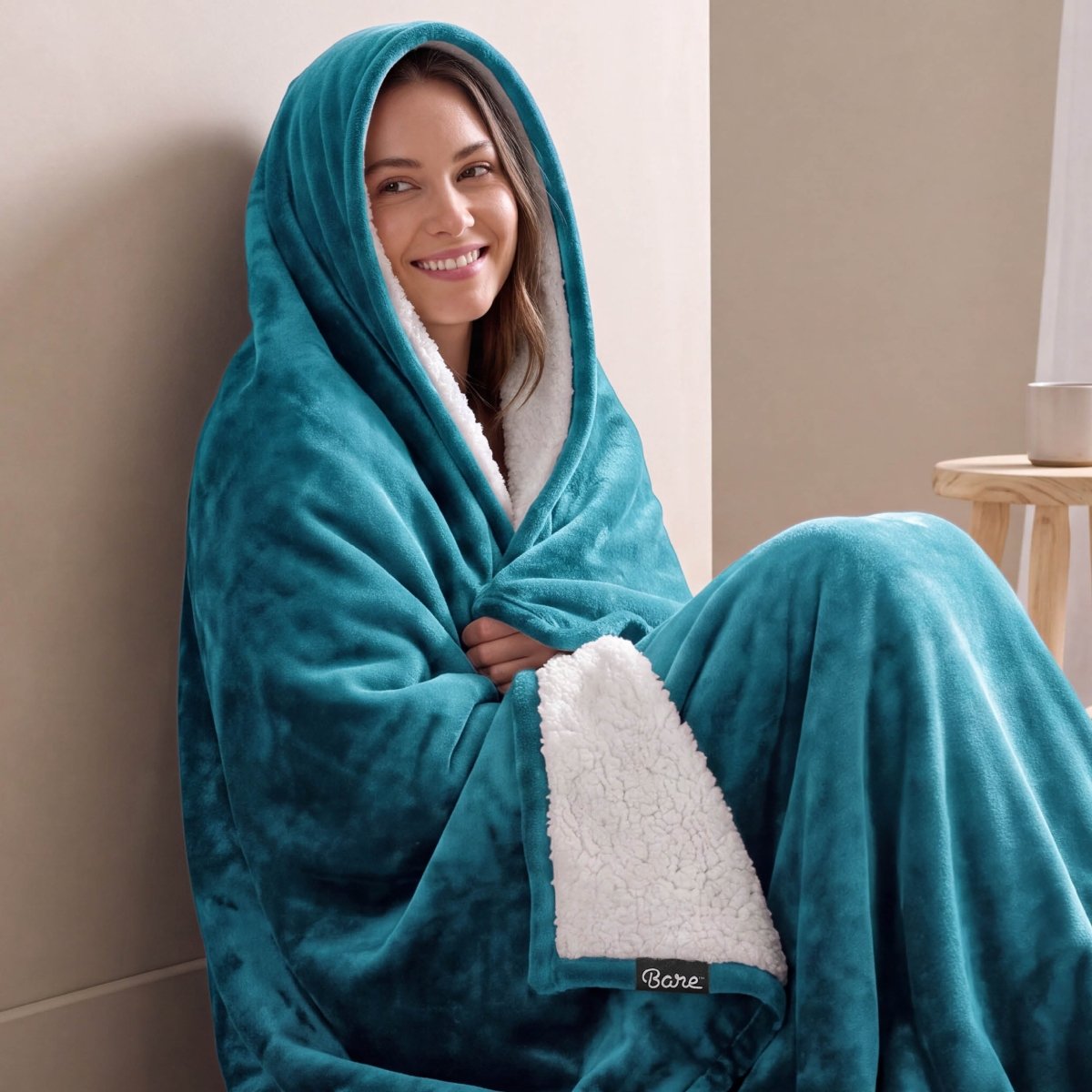 A woman is sitting with a sherpa blanket wrapped around her head and body