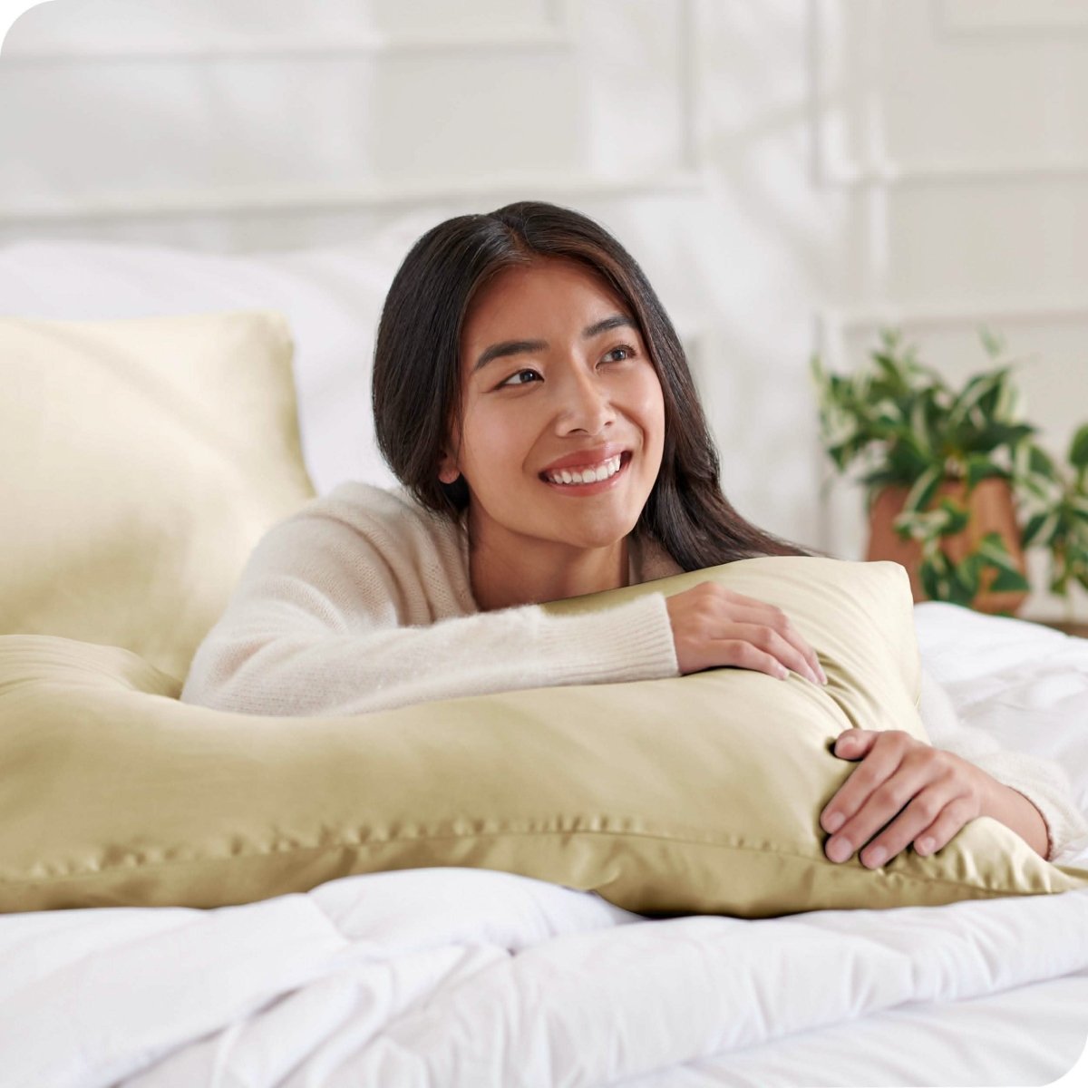 A woman on a bed with a silk pillowcase covered pillow