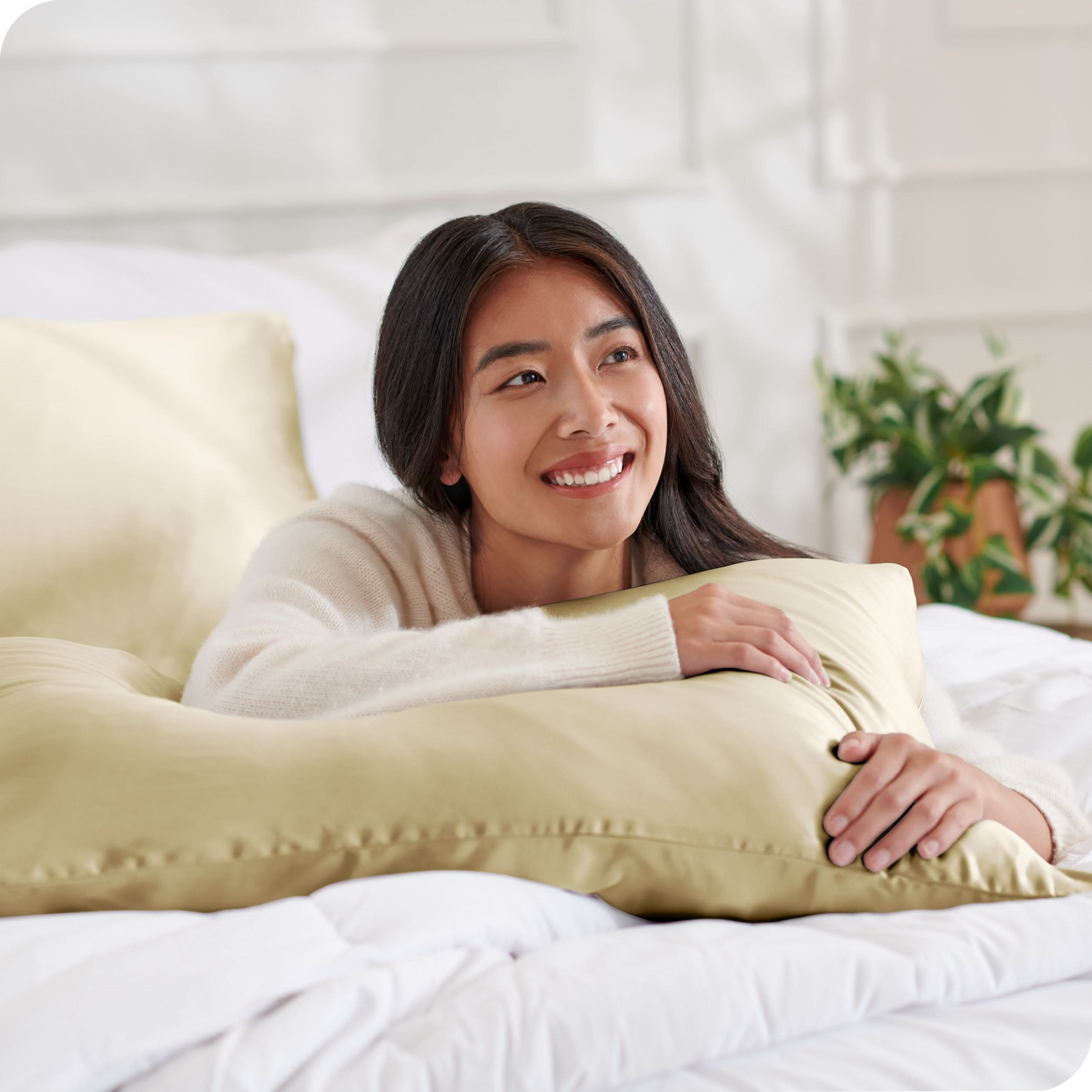 A woman on a bed with a silk pillowcase covered pillow