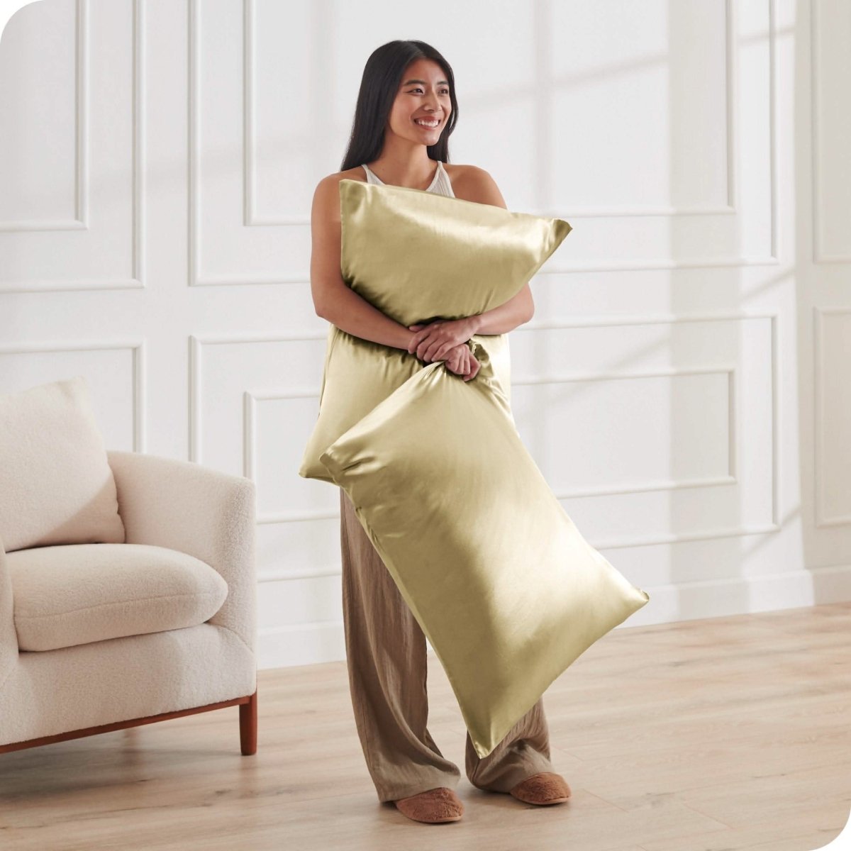 A woman standing while holding pillows with silk pillowcases on them