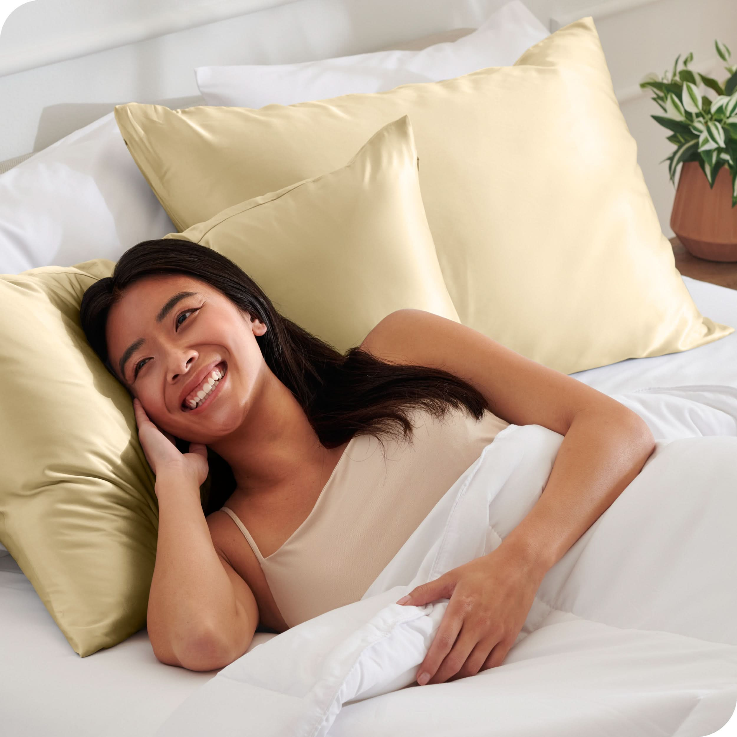 A woman is in bed and resting her head on a satin pillowcase