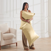 Woman holding 2 pillows with satin pillowcases on them