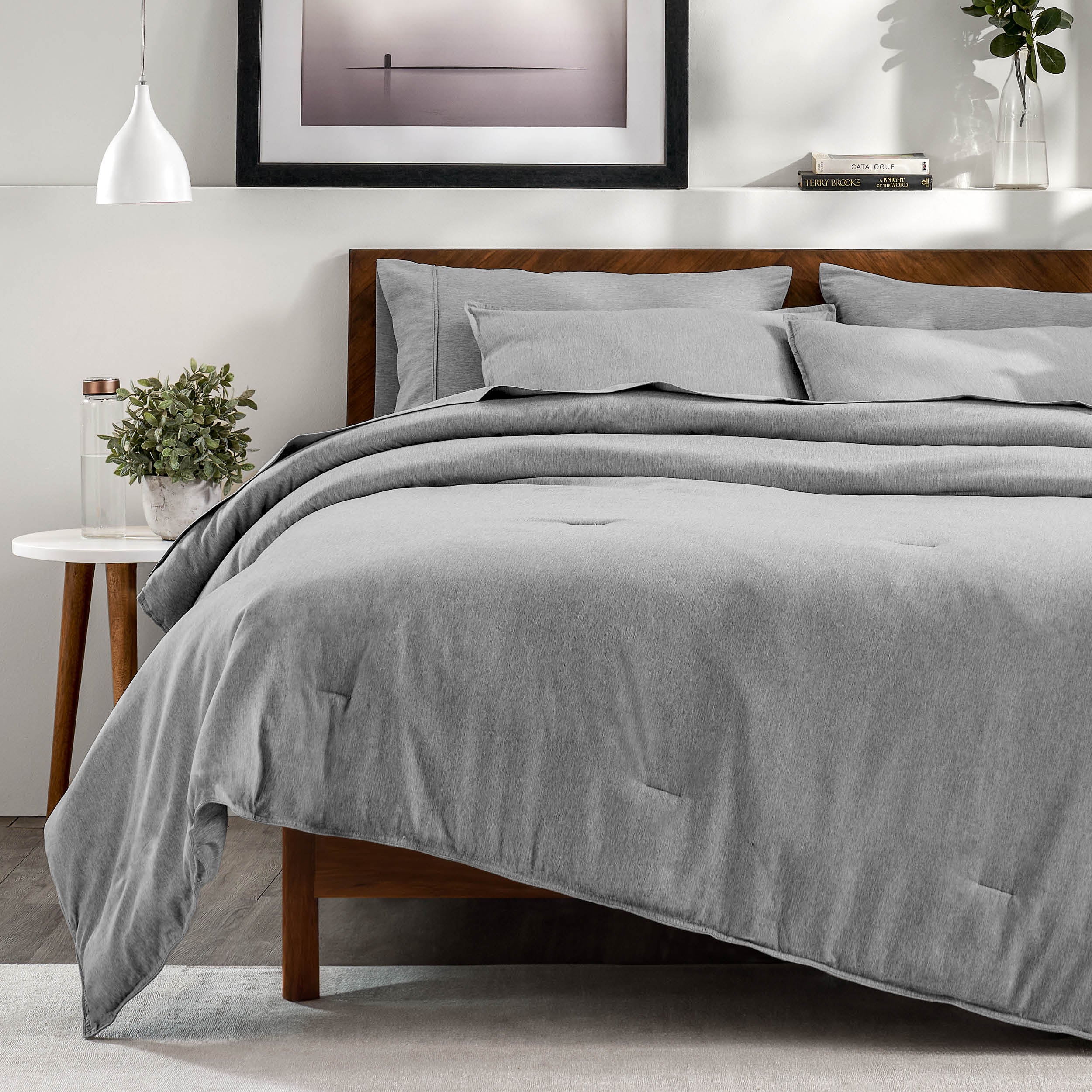 A bedroom with a side table, decor and a neatly made bed