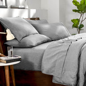Bedding set on a bed in a bedroom with a side table and lamp.