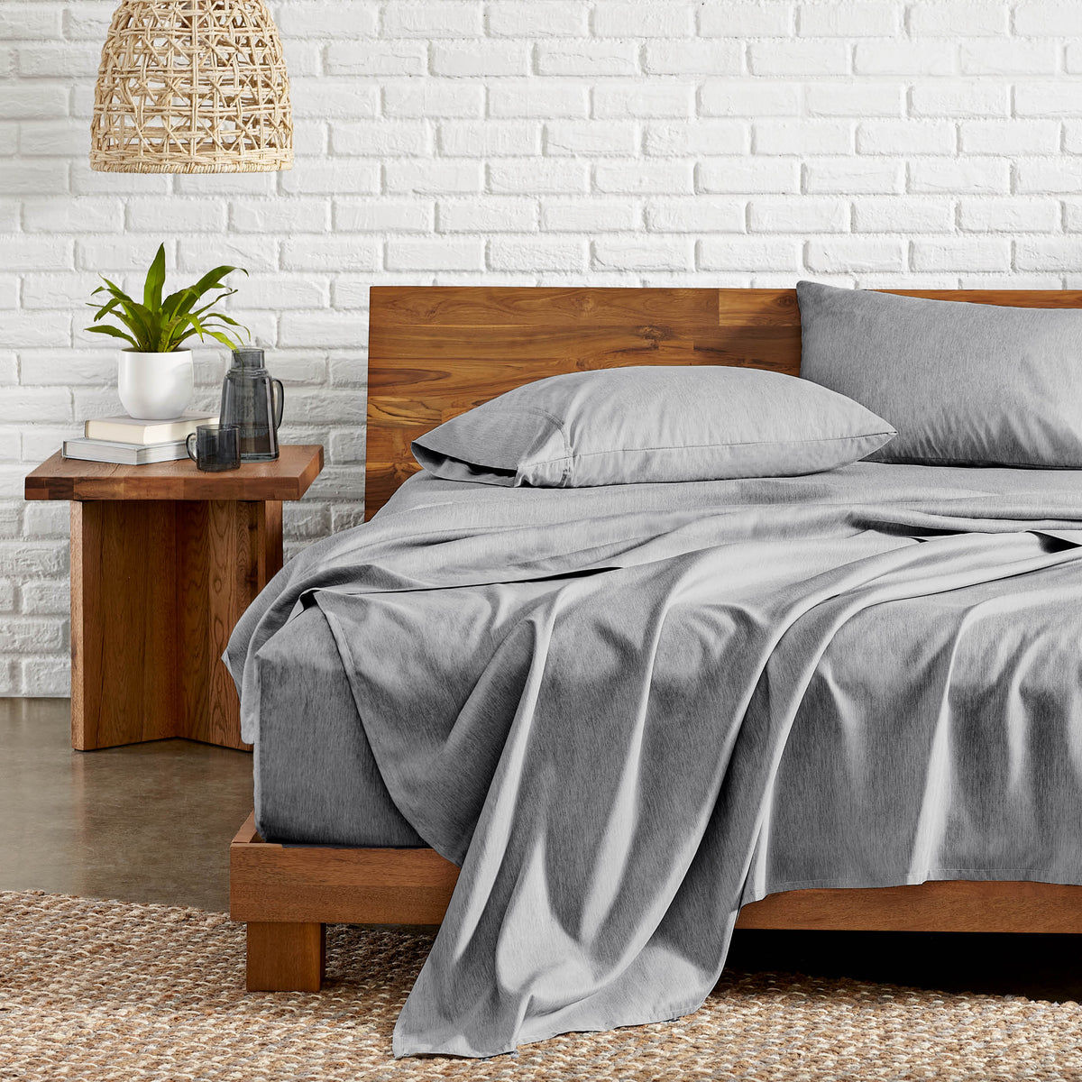 Bedroom with wooden bed, nightstand, and white brick wall.