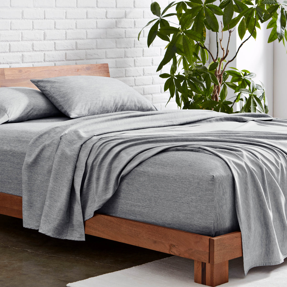 Microfiber sheet set on a wooden bed with a plant in the background