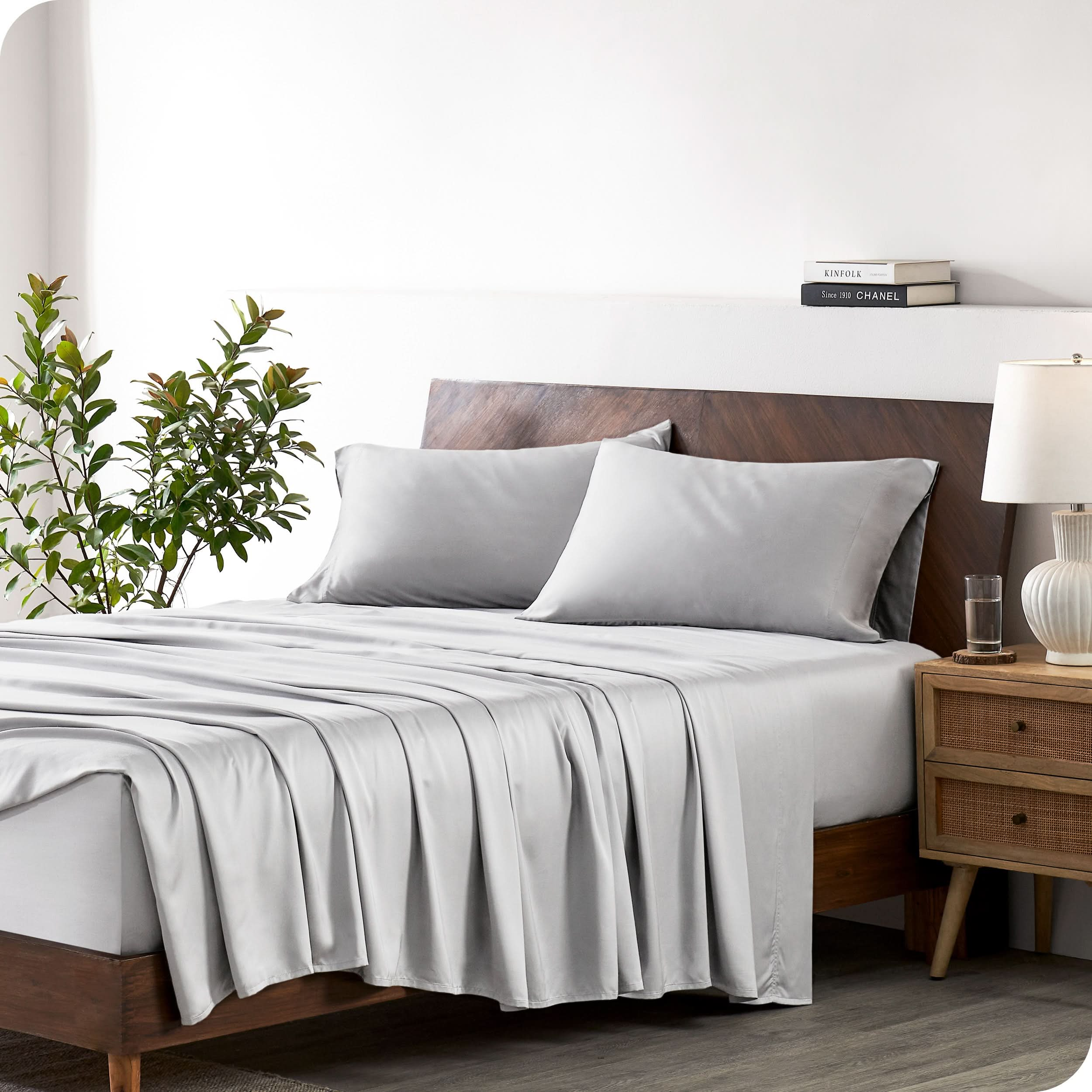 A bamboo sheet set draped over a bed with a wooden bed frame