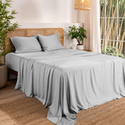 Bamboo sheets on a bed in a bedroom with plants and a lamp.