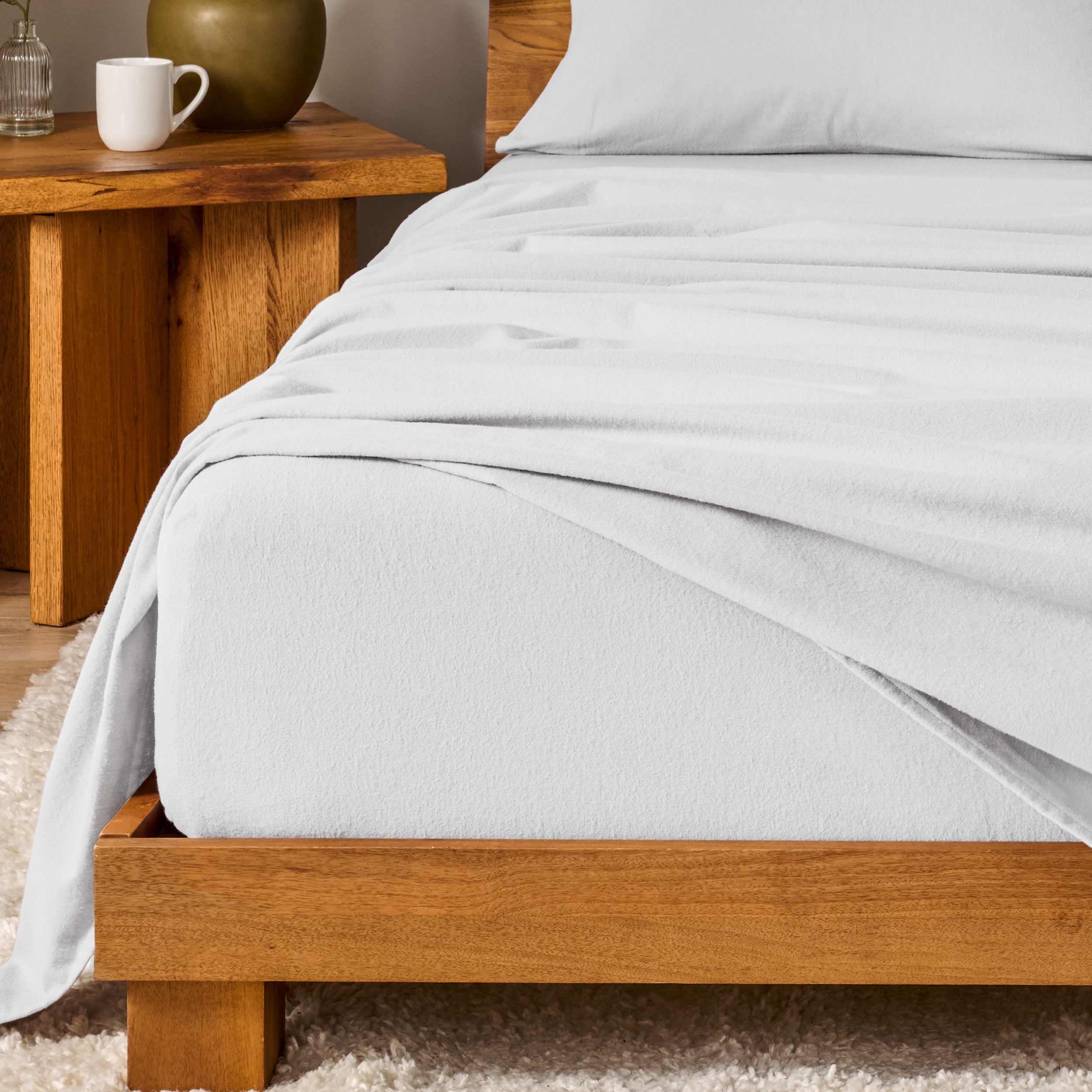 Bed with flannel bedding and wooden headboard and nightstand next to it.