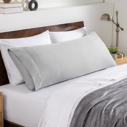 Bed sheets and pillows on a neatly made bed with a wooden headboard.