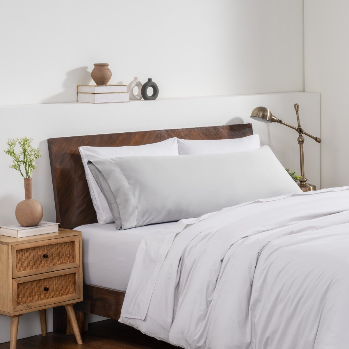 Bedroom with a wooden headboard and white bedding, featuring a nightstand and decorative items.