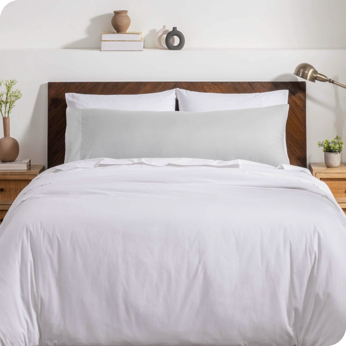 A body pillow cover on a pillow on a bed with other pillows and a duvet cover