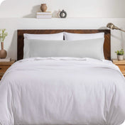 A body pillow cover on a pillow on a bed with other pillows and a duvet cover