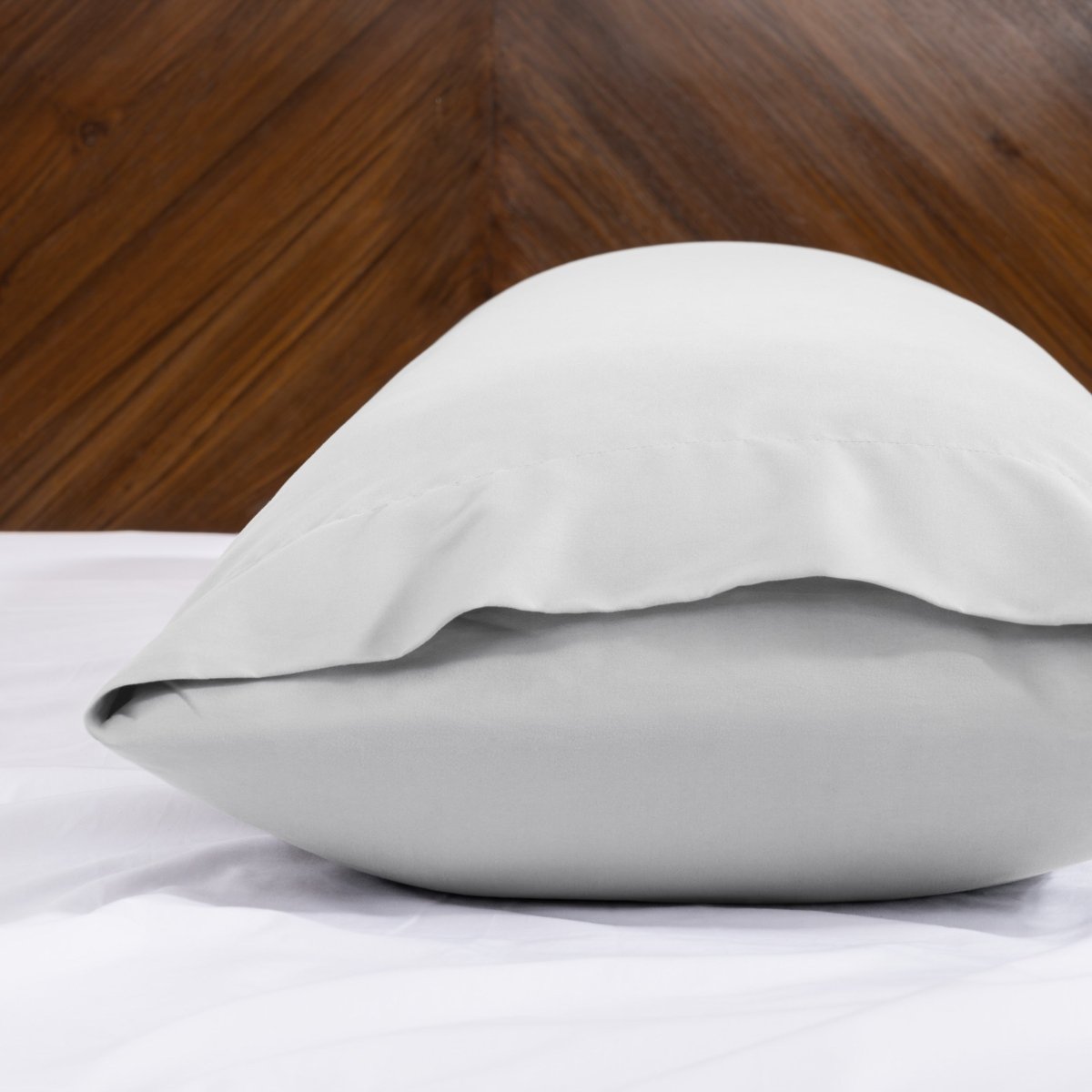 Body pillowcase with an envelope closure on a bed with a wooden headboard