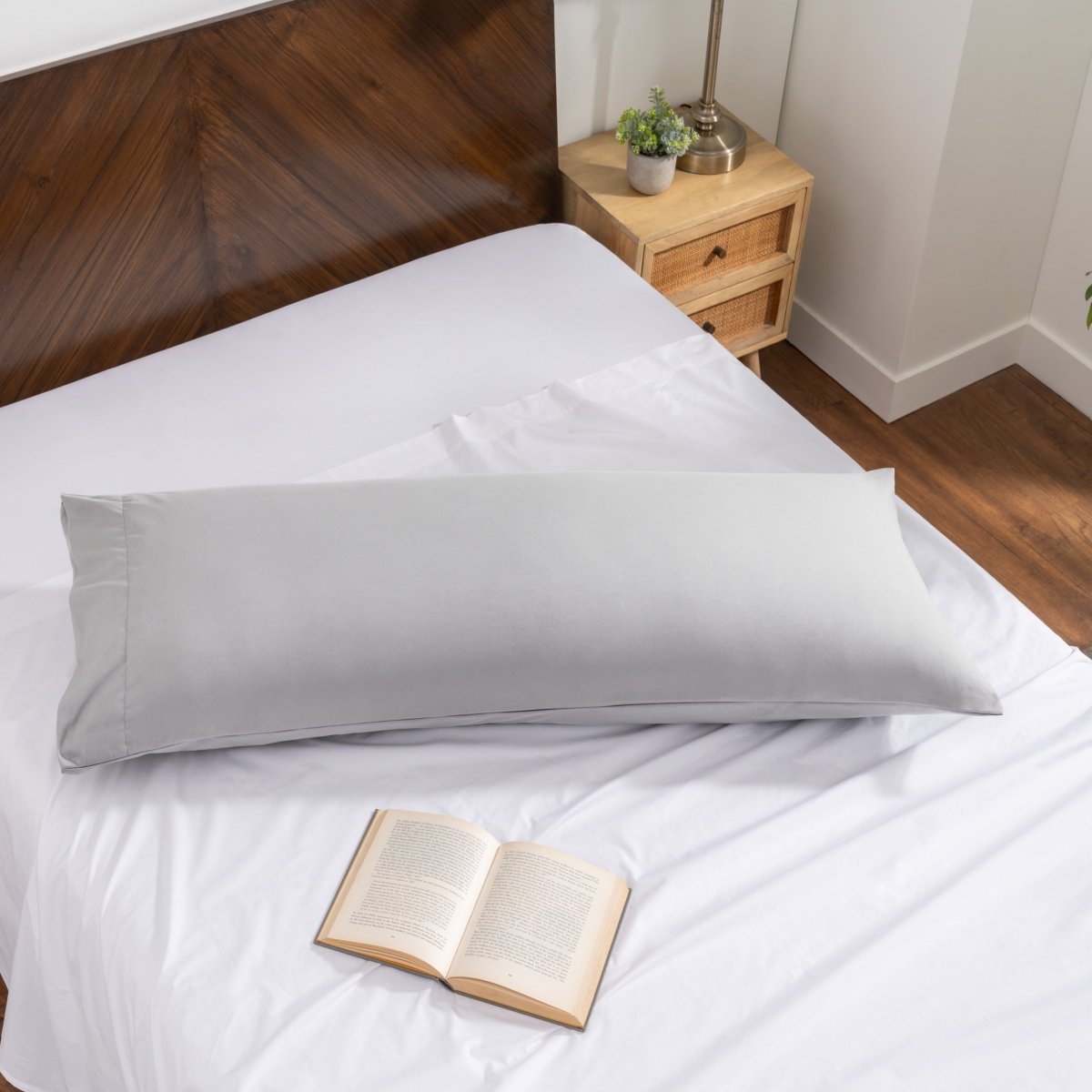Pillowcase on a body pillow with a wooden headboard and plant in the background