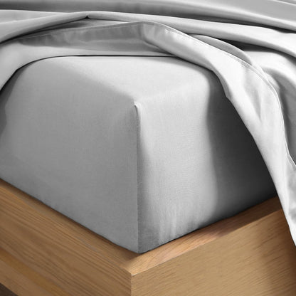 A close-up of a fitted sheet covering the corner of a bed frame, with matching top sheet draped over it.